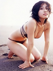 Erotic asian beauty laying around on the beach in her bikini